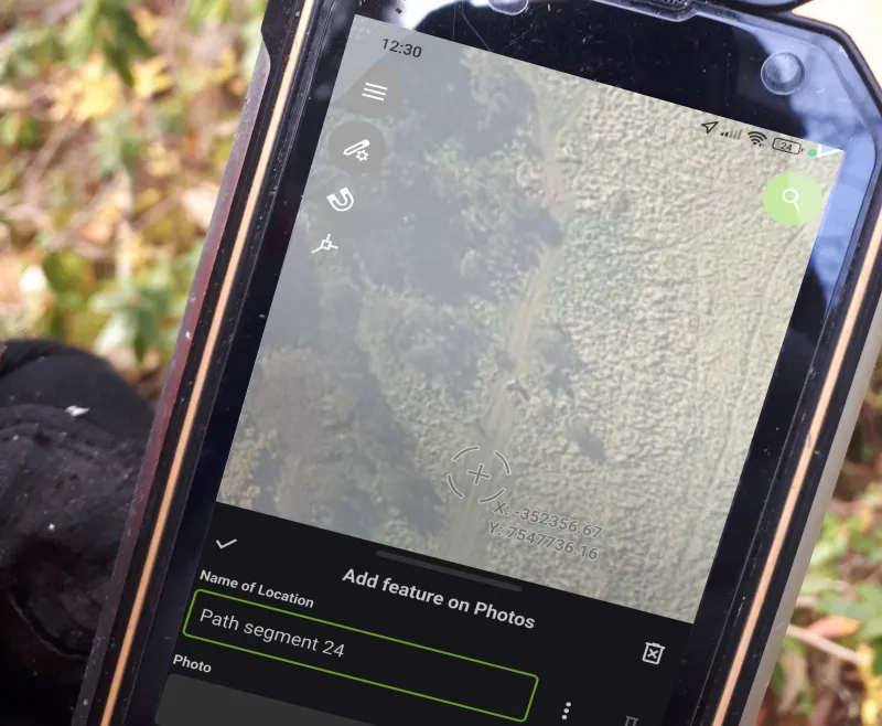 A phone running QField in the field, with a form open over an aerial image.